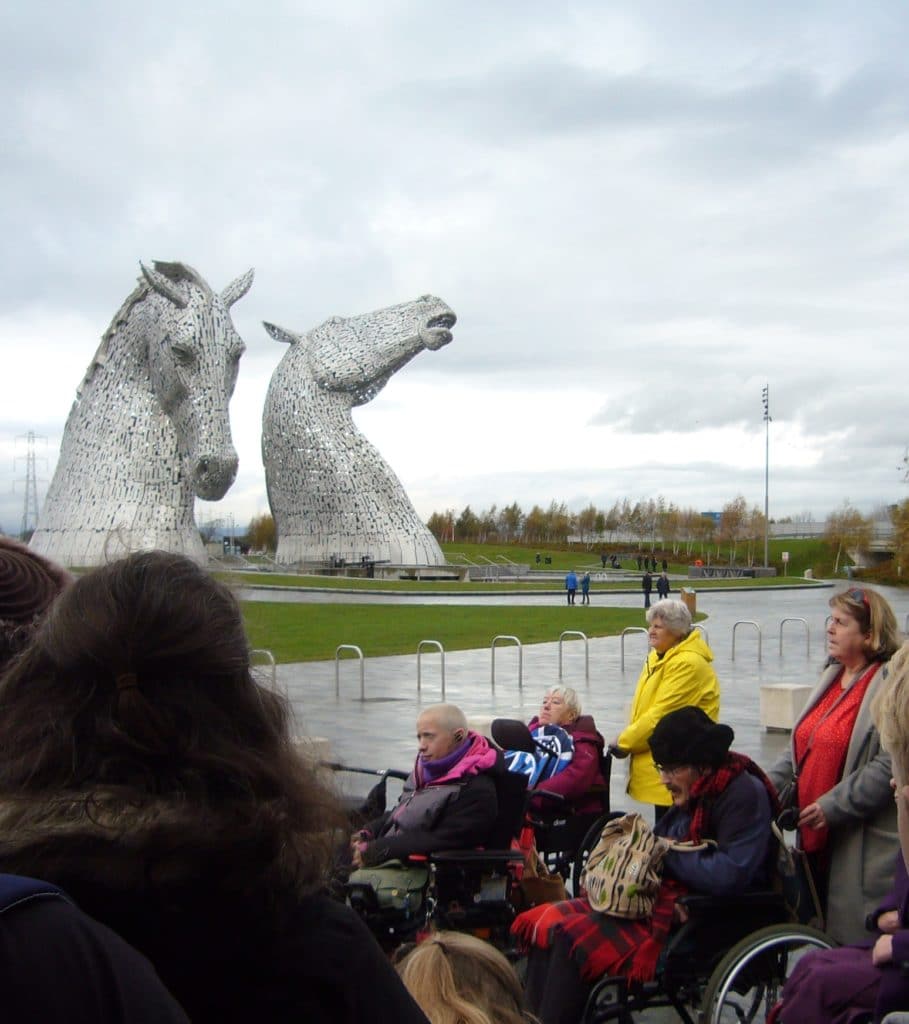 Art group taking in the views of The Kelpies on a cloudy by happy day.